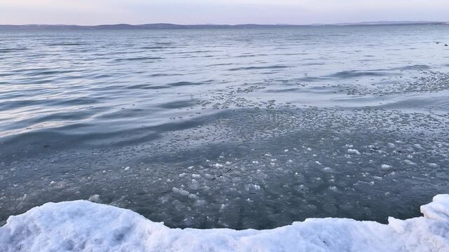Winter sunset over Lake Balaton with icy snowy shore and calm water in Hungary