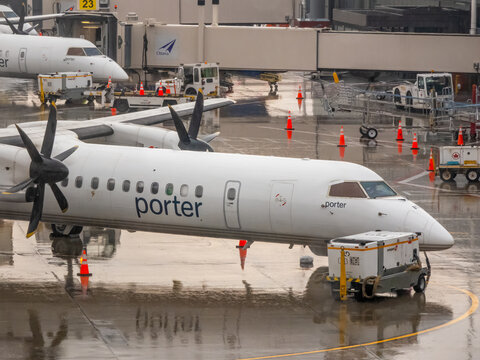 OTTAWA, ONTARIO, CANADA. SEPTEMBER 10, 2026. Porter Airlines turboprop aircraft parked at airport jet bridge gate on wet tarmac.