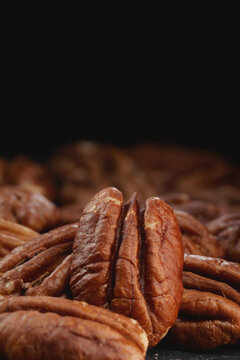 Extreme macro shot of fresh premium pecan nuts with selective focus on dark background with artistic lighting. Perfect for healthy eating, gourmet food, culinary, and dietary content.