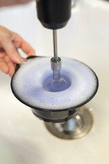 Mixing liquid in a black bowl with a hand-held device in a kitchen setting © aleksa_photo_waw