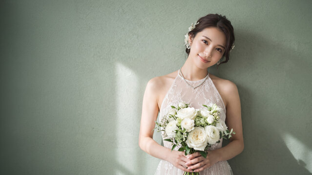 花束を持ち微笑むウェディングドレス姿の女性