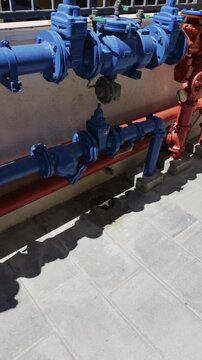 Residential home water supply and fire suppression system with blue and orange industrial pumps mounted on concrete wall