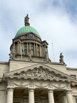The historic Custom House in Dublin features a copper-green dome, classical columns, statues and ornate stonework beneath a cloudy Irish sky.