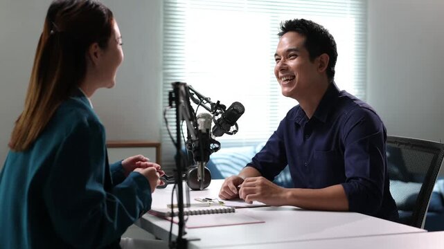 Young man and woman podcasters talking and interviewing each other for their online audio broadcast.