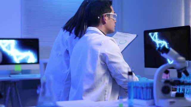 Male and female scientists are analyzing and discussing together in a laboratory.