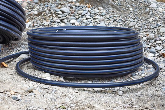Coil of black HDPE pipe on gravel