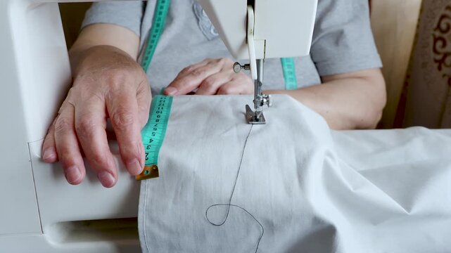 Senior Woman Measuring Fabric with Tape for Home Sewing Project