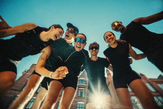 Team energy surrounds the running friends in a sunny outdoor huddle