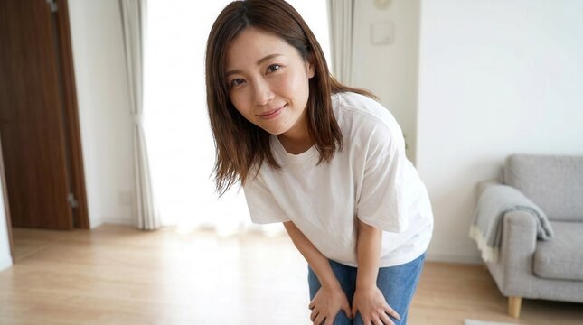 Woman in a white t-shirt leaning forward in a room