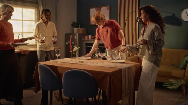 Diverse multiethnic young adult friends setting dining table with plates and candles for festive celebration at home. Perfect for Friendsgiving ads and lifestyle marketing