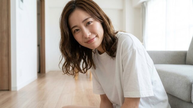 A woman wearing a white t-shirt leaning forward inside a room