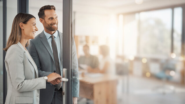 Business partners unlocking door to new office with blurred corporate space background banner.
