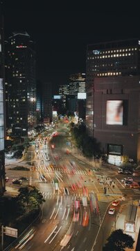 Urban nighttime scene featuring illuminated skyscrapers and busy streets with flowing traffic in a lively city environment. Time-lapse, Seoul, South Korea