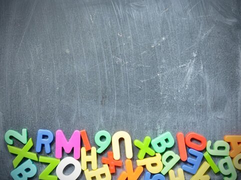 Colorful plastic alphabet letters on a dark chalkboard background with ample copy space