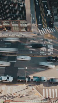 Aerial perspective of a bustling city street with various vehicles navigating through traffic and pedestrian crosswalks visible. Time-lapse, Seoul, South Korea