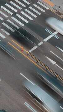 Vehicles in motion navigate crosswalks on a busy urban street with traffic lights and road markings visible. Time-lapse, Seoul, South Korea