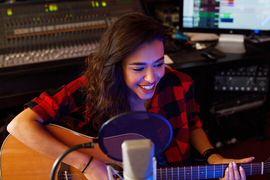 Smiling woman singer recording her song in studio
