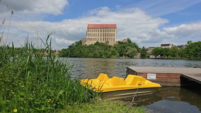 Yellow paddle boats tied to wooden dock with Plumlov Castle background