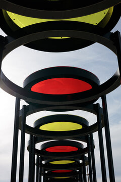 Abstract view of a modern metal sculpture with red and yellow rings against the sky