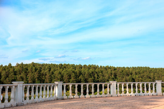 White stone balustrade on an observation deck overlooking a green pine forest