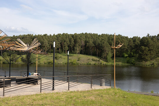 Modern wooden pavilion and pier on a lake shore with pine forest