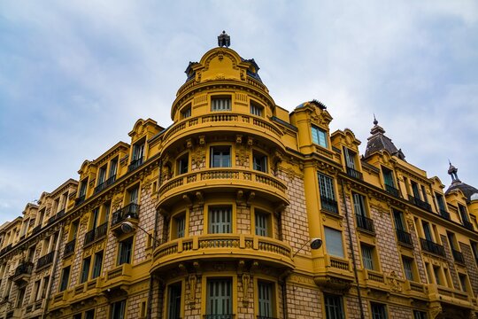 Ornate yellow building with rounded balconies against cloudy sky