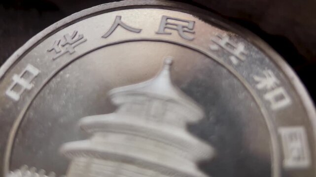 Macro video showing the reverse side of a 1996 Chinese 10 yuan silver Panda coin, featuring Temple of Heaven architectural relief, raised Chinese lettering, polished silver surface, and rim details.