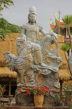 Stone Guanyin statue sitting on lunar zodiac rooster mount, traditional Asian astrology cockerel bird sculpture for punctuality and courage
