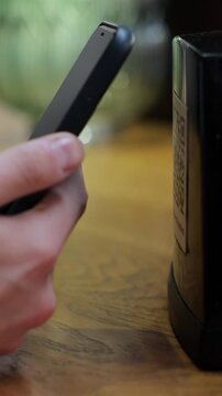 Vertical video. Unrecognizable man scanning QR code on table in restaurant or cafe. Online menu for clients. Convenience, contactless concept.