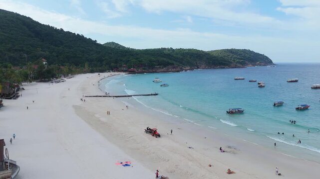 Aerial view of people relaxing and walking on tropical white sand beach along clear sea, Redang Island, Malaysia