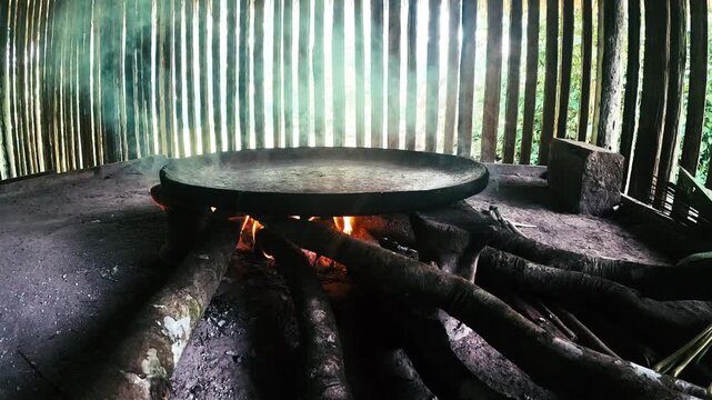 Large Traditional Cooking Pan Over Fire in Ecuador Amazon House, Wooden Interior, Smoke, Rural Food Preparation and Indigenous Community Culture