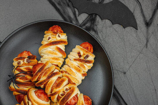 Spooky sausage mummies for Halloween party. Funny seasonal food, homemade baking, traditional decor