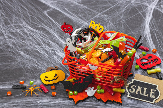 Full of sweets basket, sale concept. Funny Halloween background. Scary spider web