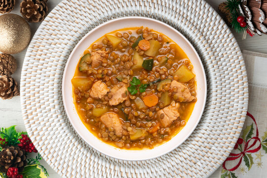 Top view of potato stew with lentils and chicken. Traditional Spanish recipe. Christmas meal with festive decorations.