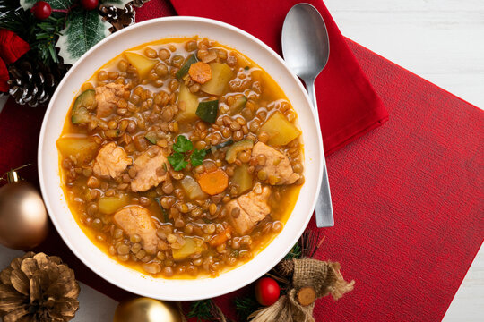 Top view of potato stew with lentils and chicken. Traditional Spanish recipe. Christmas meal with festive decorations.