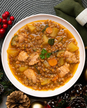 Top view of potato stew with lentils and chicken. Traditional Spanish recipe. Christmas meal with festive decorations.