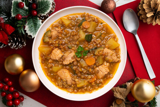Top view of potato stew with lentils and chicken. Traditional Spanish recipe. Christmas meal with festive decorations.