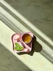 Aesthetic morning skincare flat lay with eye patches, jade roller and gua sha on a pink plate under sunlight shadows © Jekaterina