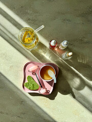 Wellness flat lay with eye patches, serum bottles, jade roller and detox lemon water under sun shadows. © Jekaterina