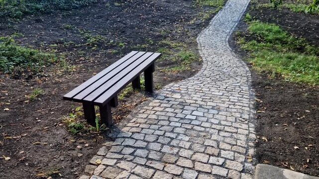 The image shows a narrow path paved with stone setts so-called cat's heads or granite cubes winding through a rural landscape or a park&mdash;such as a ch&acirc;teau park or wooded park.