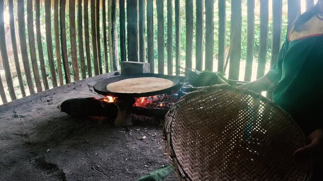 Traditional Cooking Fire Inside Wooden Amazon House in Ecuador, Round Pan Over Firewood Stove, Smoke, Woven Basket and Rural Indigenous Food Preparation Scene