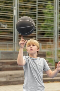 Child Spinning Basketball on Finger Outdoors