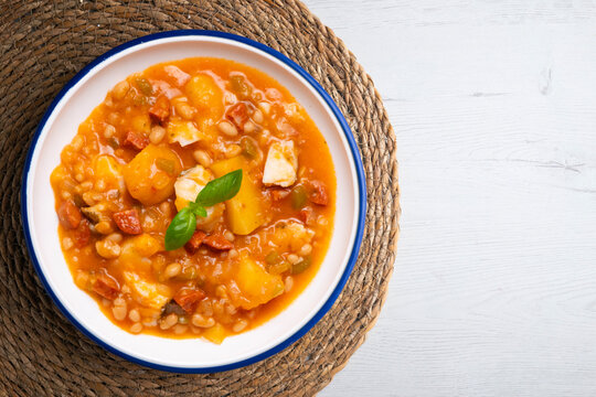 A close-up overhead view of a delicious cod and chorizo stew, garnished with basil