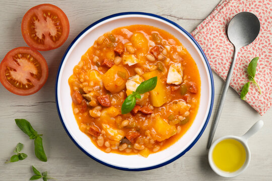A close-up overhead view of a delicious cod and chorizo stew, garnished with basil