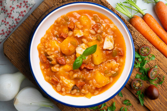 A close-up overhead view of a delicious cod and chorizo stew, garnished with basil