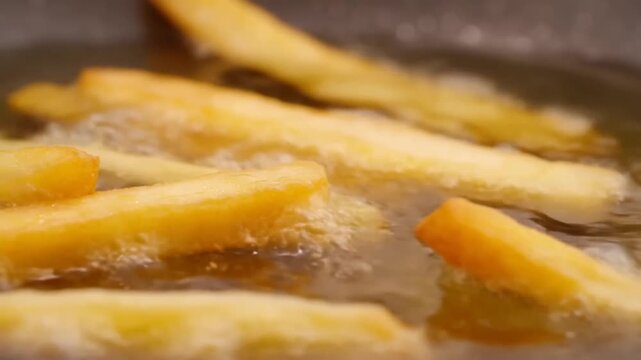 French fries frying in hot oil in a deep fryer with bubbles rising around them