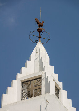 Rooster-shaped weathervane on top of a white church tower against a blue sky, Benguela Province, Benguela, Angola