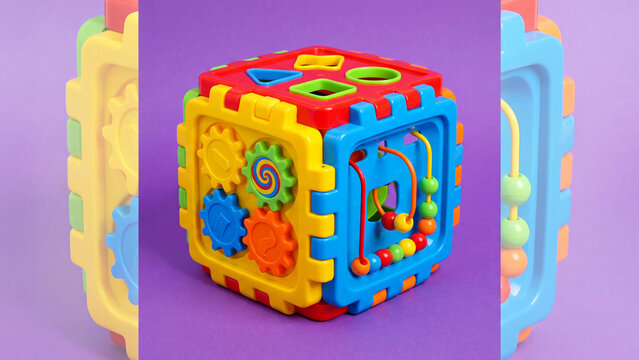 Colorful plastic activity cube educational toy with gears shape sorter bead maze on purple background for kids learning motor skills sensory development creative play and preschool education