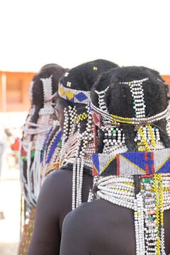 Three Handa women seen from behind wearing beaded headdresses and collars, Huila Province, Hoque, Angola