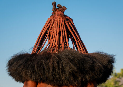 Rear view of a woman's head showing red ochre-coated hair strands over a thick black fiber fringe, Cunene Province, Oncocua, Angola